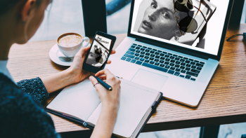 persoon kijkt naar een beeld op mobiel in de hand, met daarachter hetzelfde beeld op een beeldscherm