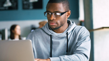 afbeelding van een persoon met bril die op een laptop kijkt